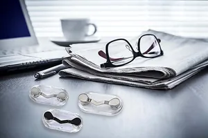 Macro detail of magnetic eyeglass holders in silver and black on office desk
