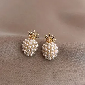 French vintage gold pineapple earrings with pearls on a brown fabric background