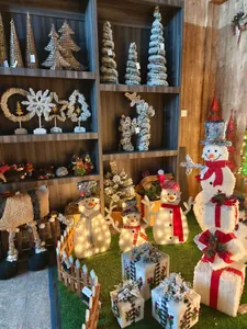 Close-up of glowing LED Christmas snowman figurine and flocked mini pine trees in a display
