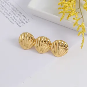 Detailed view of golden shell hair clip with glossy metal finish and textured fan design