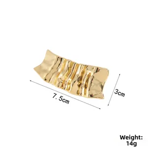 Detailed close-up of wavy gold metal hair accessory with 7.5cm x 3cm dimensions