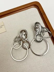 Detailed view of silver ear-shaped earrings featuring layered rings with zircon accents