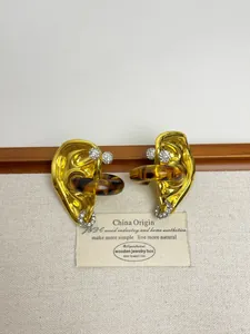 Macro detail of vintage gold ear-shaped studs with amber resin and sparkling crystals