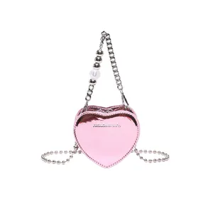 Pink heart-shaped crossbody bag with metallic finish and silver chain strap