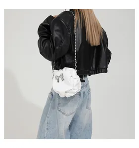 Détail du sac bandoulière blanc plissé avec nœud argenté et bandoulière en chaîne