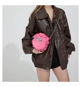 Détail du sac à bandoulière plissé rose avec un nœud en métal argenté et une bandoulière chaîne
