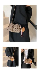 Detalle de bolso saco de cuadros con lazos negros, cordón y colgante de oso de peluche