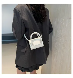 Detailed view of white mini cross-body bag worn over a grey blazer for styling