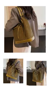 Detail of olive green suede bucket bag featuring drawstring closure and stylish bow tie