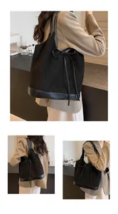Detail of black suede tote bag with leather contrast bow and spacious shoulder design
