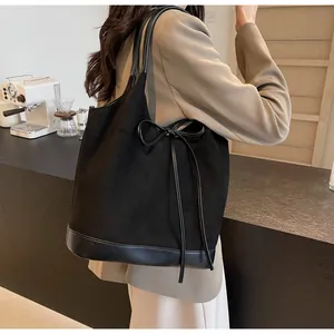 Detail shot of black frosted tote bag with bow ribbon and leather splicing design