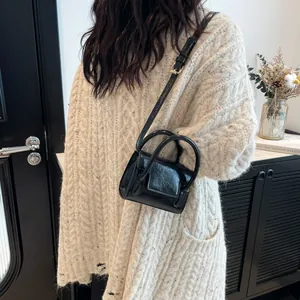 Chic black mini crossbody bag with cracked leather finish and unique round handles