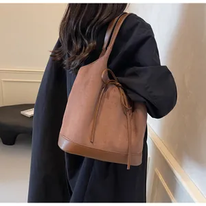 Detail of a brown matte suede tote bag with leather bow and contrasting bottom panel