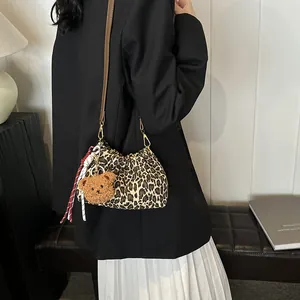 Bolso saco plisado con estampado de leopardo y colgante de oso llevado por modelo