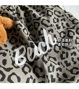 Detail shot of leopard print canvas tote bag with Beach typography and soft fabric texture