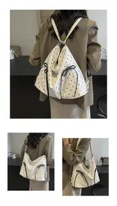 Detailed close-up of white polka dot tote with bow accents and multi-way shoulder straps
