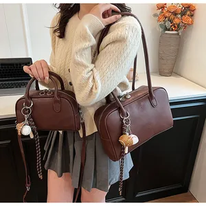 Detail of two vintage brown leather Boston bags in different sizes with baseball charms