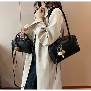 Detail of black leather shoulder and crossbody bags with baseball charms on a beige coat