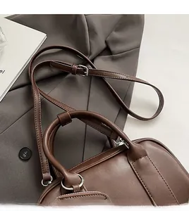 Detail of adjustable leather shoulder strap and silver metal buckle on brown bag