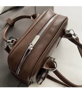 Detail of silver smooth zipper and dark brown leather texture on a Boston handbag
