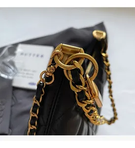 Détail macro de la chaîne en métal doré brillant sur un sac en cuir noir matelassé