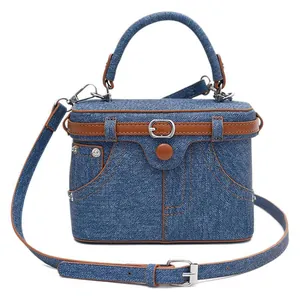 Blue denim crossbody box bag with brown leather trim and retro pocket design details