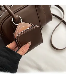 Close-up of small brown leather square bag showing internal storage capacity with zipper