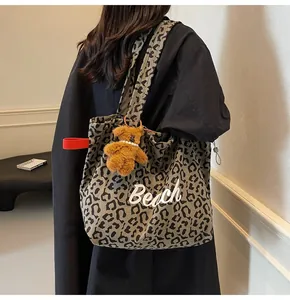 Detail of canvas leopard print tote bag with Beach print and plush bear charm