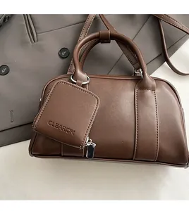Detail of dark brown leather pillow bag with CLEAROK logo and square charm attachment