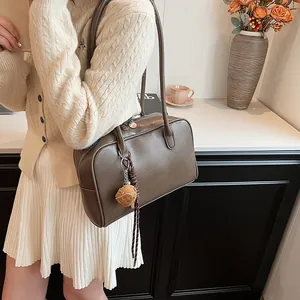 Retro brown Boston shoulder bag with top handle and dice charm shown in lifestyle setting