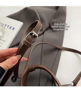 Detail of adjustable dark brown leather shoulder strap with silver buckle hardware