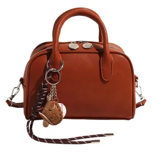 Caramel brown vintage commuter bowling bag with baseball charm and dual handles