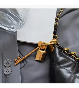 Détail d'un sac en cuir noir matelassé avec chaîne dorée et pendentifs de clé stylés