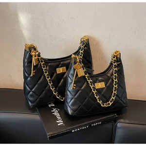 Gros plan de sac hobo en cuir matelassé noir avec chaîne dorée et pendentif cadenas
