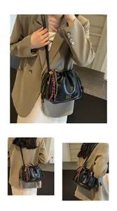 Detail of black drawstring bucket bag with gold logo and woven rope accent