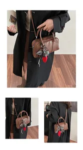 Detailed view of a brown leather Boston bag featuring decorative bow and cartoon charms