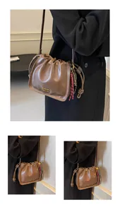 Detail view of brown leather bucket bag with drawstring closure and golden logo