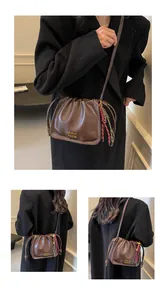 Detail of vintage brown drawstring bucket bag with gold lettering and colorful charm