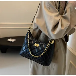 Gros plan d'un sac à bandoulière en cuir noir matelassé avec chaîne dorée et fermoir pivotant