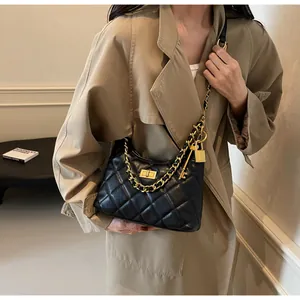 Détail du sac hobo en cuir matelassé noir avec chaîne dorée et breloque cadenas luxe