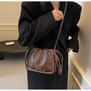 Detail of vintage brown leather bucket bag with gold lettering and woven drawstring charms