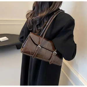 Dettaglio di una borsa a spalla vintage in pelle cerata marrone scuro con fibbie argento