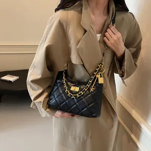 Sac à bandoulière matelassé en cuir avec chaîne dorée porté par un mannequin en trench