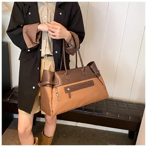 Detail of contrast-color tote bag featuring side buckles and functional front zipper pocket