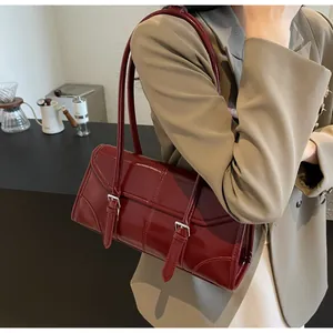 Borsa a spalla in pelle cerata rosso-marrone indossata con un blazer beige