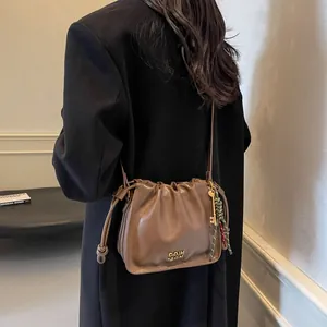 Retro brown drawstring bucket bag in premium leather finish with gold hardware and woven detail