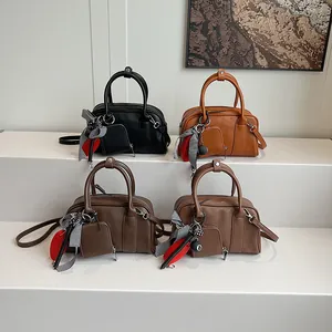 Mini Boston bags in four colors with charms and scarves on white display stand