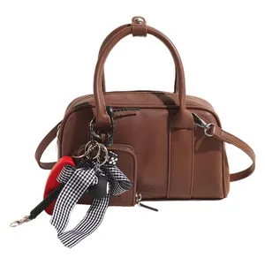 Brown Boston handbag in faux leather with circular handles and a decorative coin purse charm