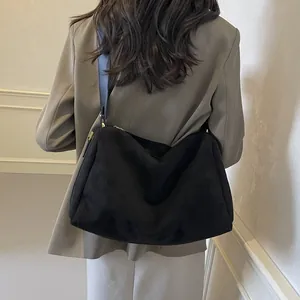 Premium black suede pillow bag with wide shoulder strap shown on model's shoulder