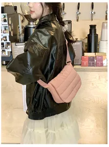 Close-up of a pink quilted puffer crossbody bag worn with a black leather jacket
